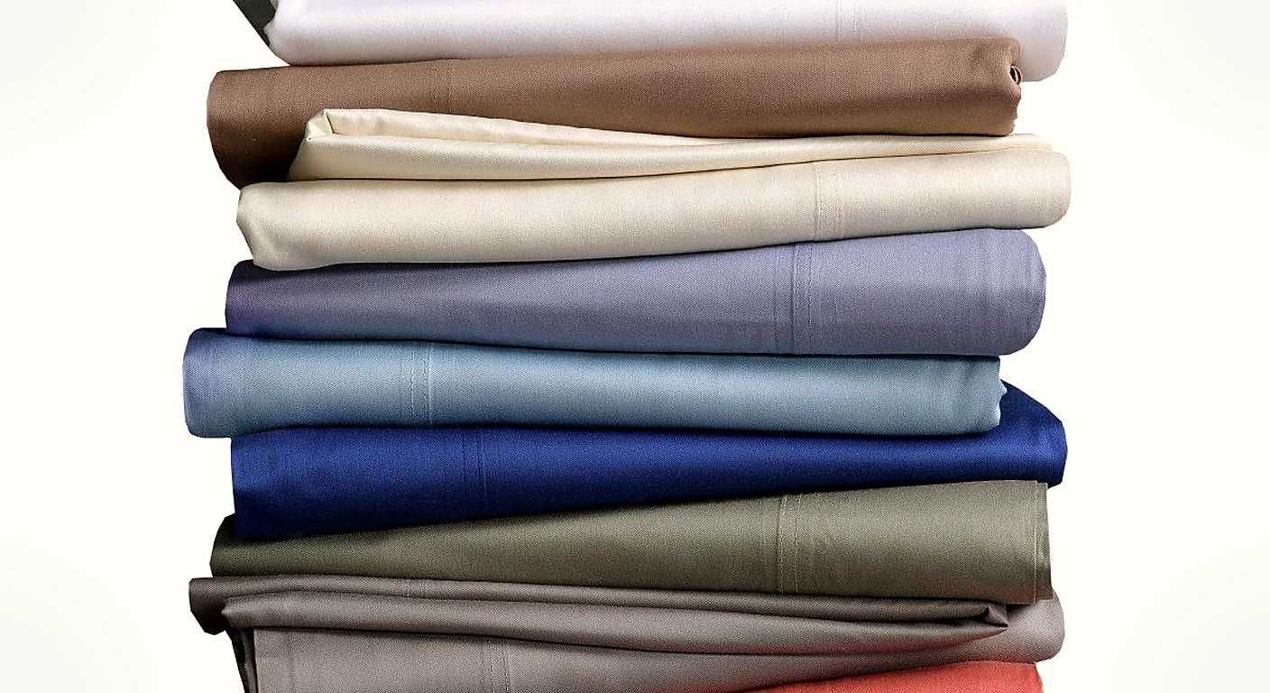 A tall stack of folded bamboo viscose sheets in many colours