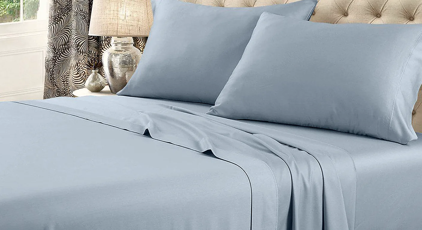 A bed made up with a blue 600 thread count flex-top king sheet set and pillowcases