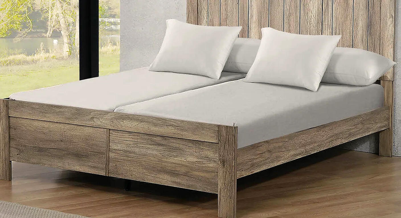 A split king bed on a wooden frame, with two separate mattresses and two grey fitted sheets