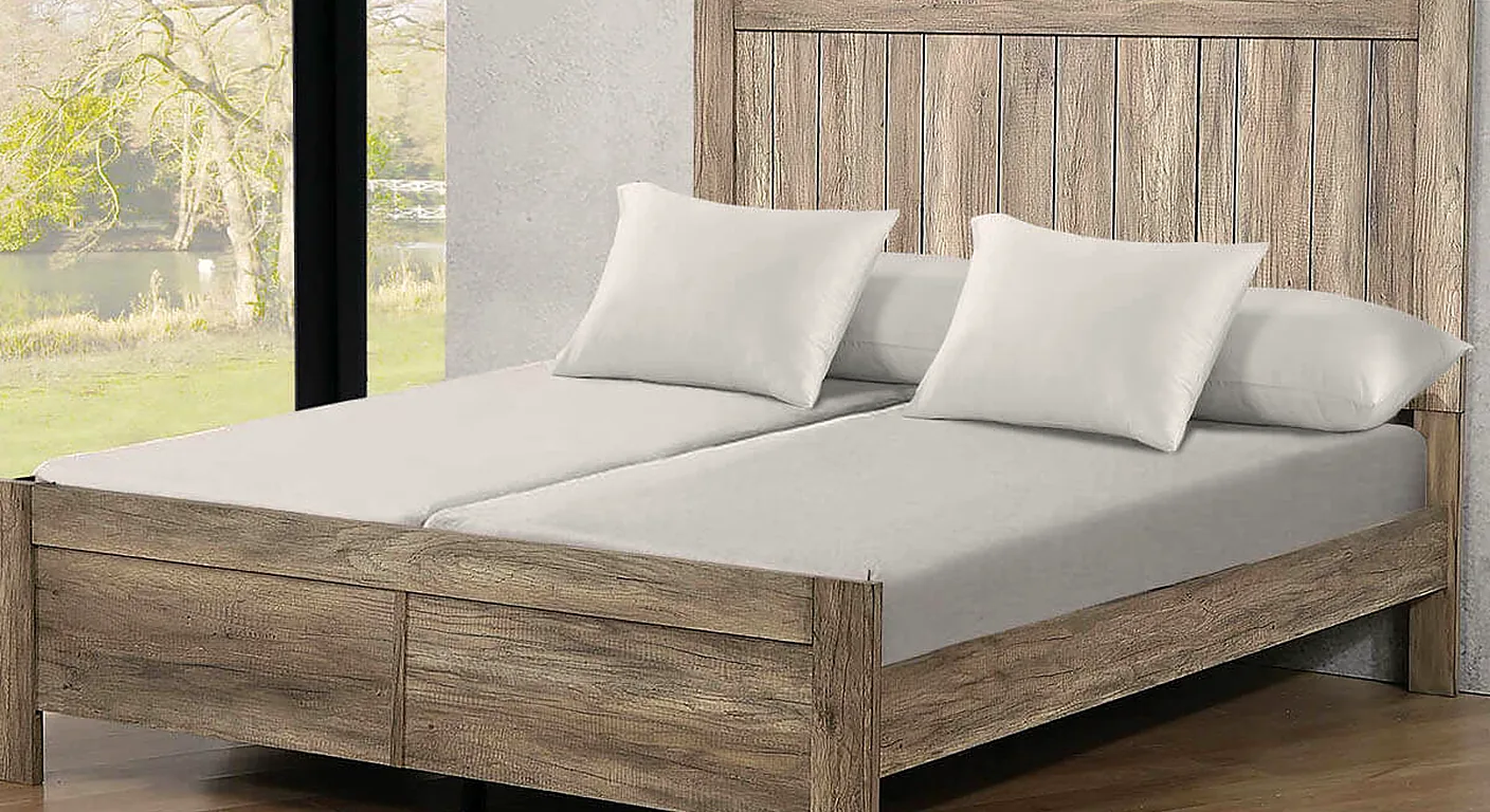 A split king bed with two separate mattresses, each with its own grey fitted sheet